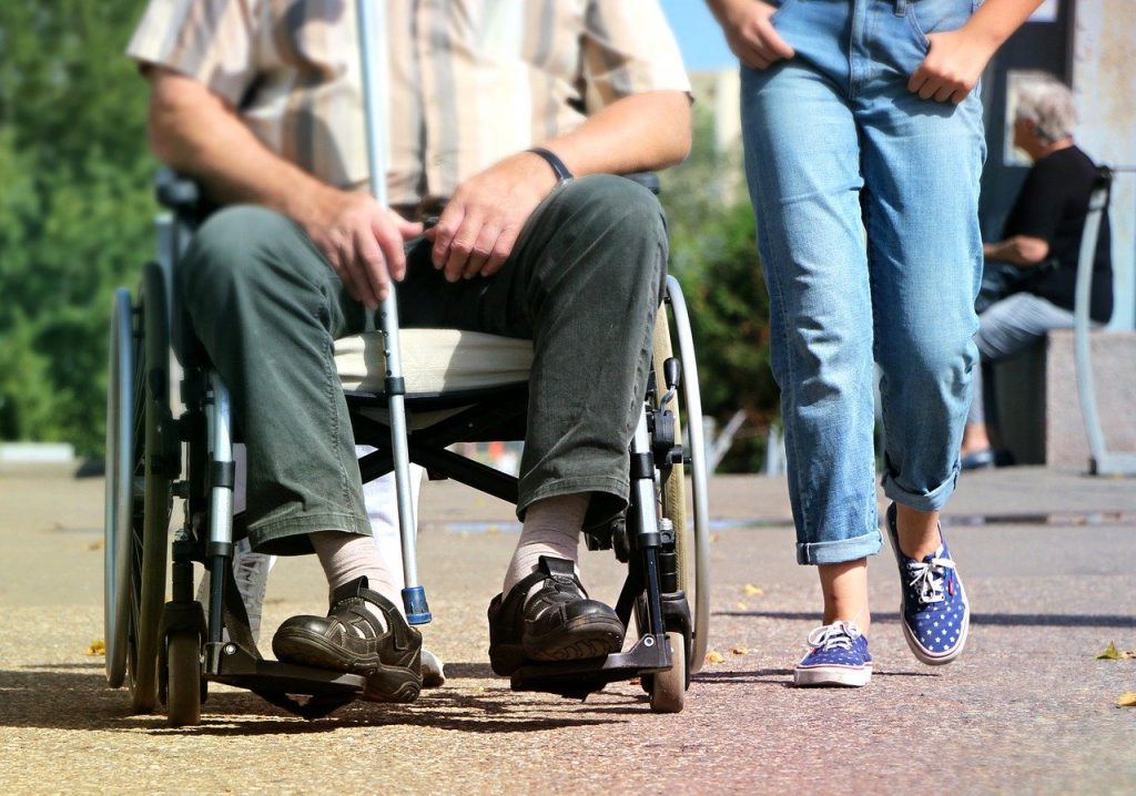 personne âgée en fauteuil roulant à côté d'une personne plus jeune